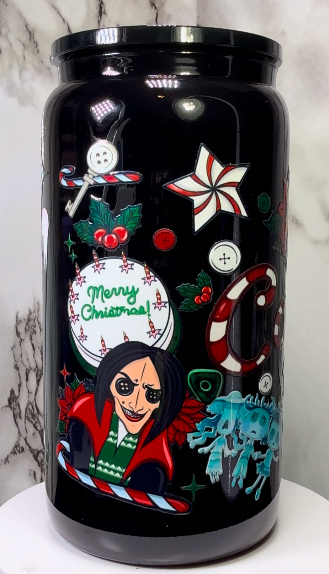Coraline Christmas UVDTF on either a black plastic or black glass beer can cup