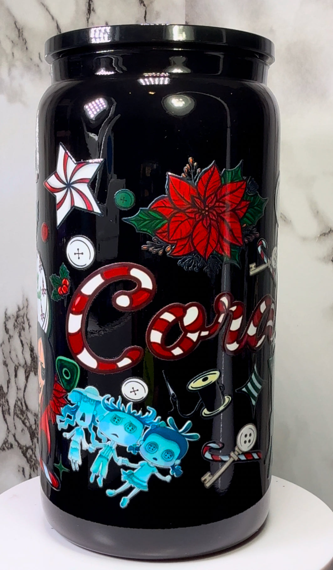 Coraline Christmas UVDTF on either a black plastic or black glass beer can cup