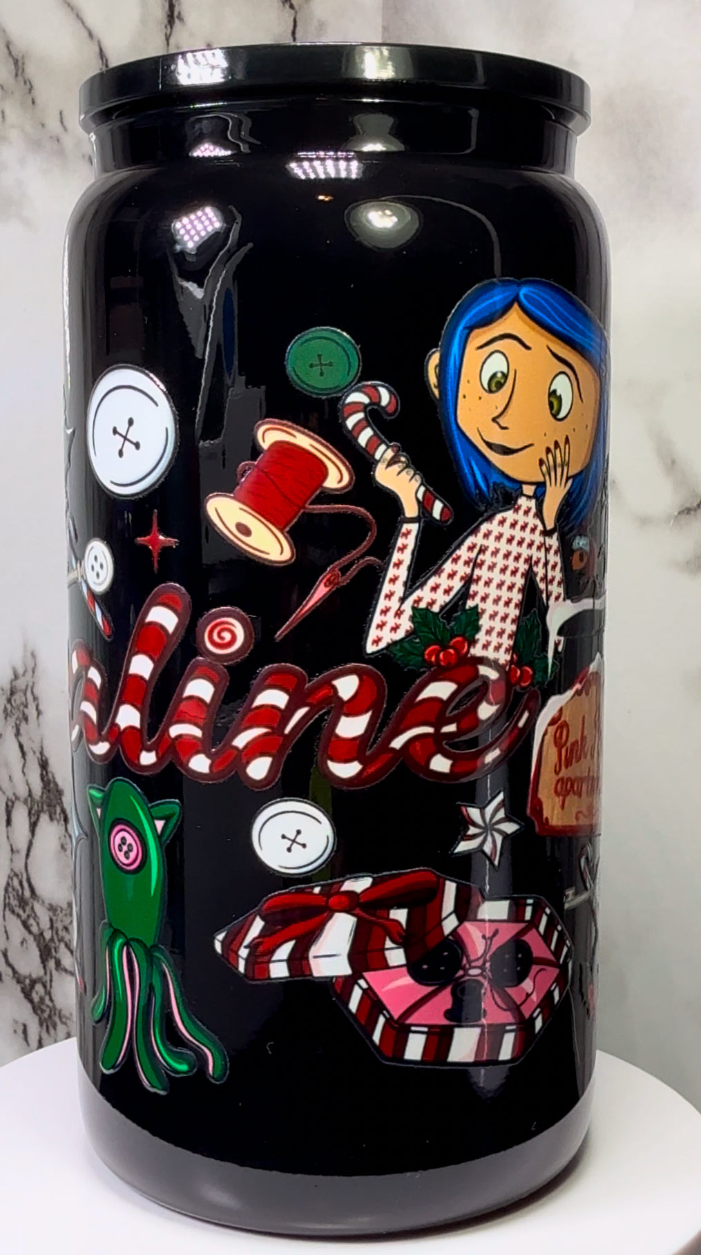 Coraline Christmas UVDTF on either a black plastic or black glass beer can cup